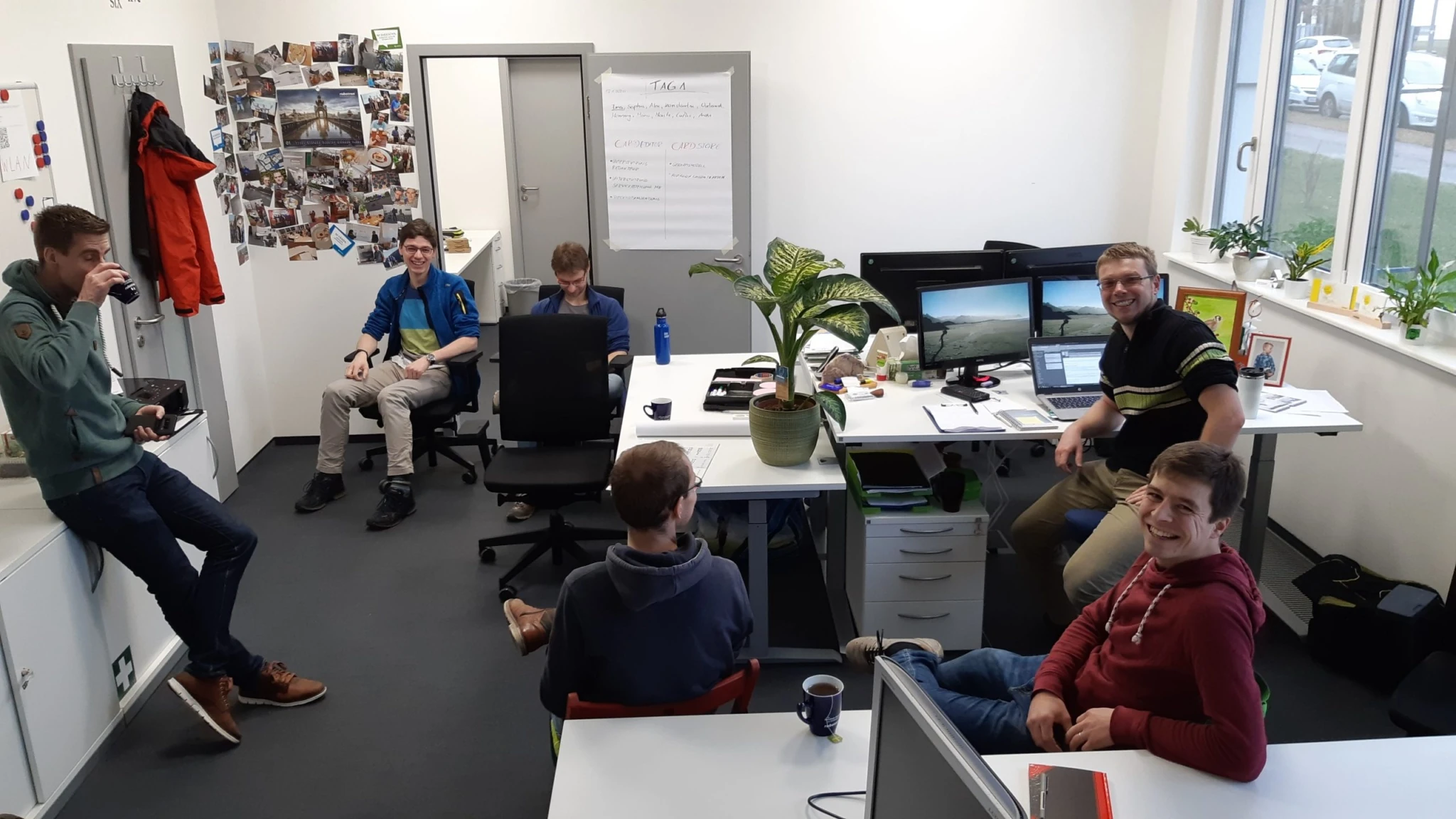 Kollegiale Gesprächsrunde im Peerox-Büro – lockere Atmosphäre mit Whiteboard im Hintergrund.
