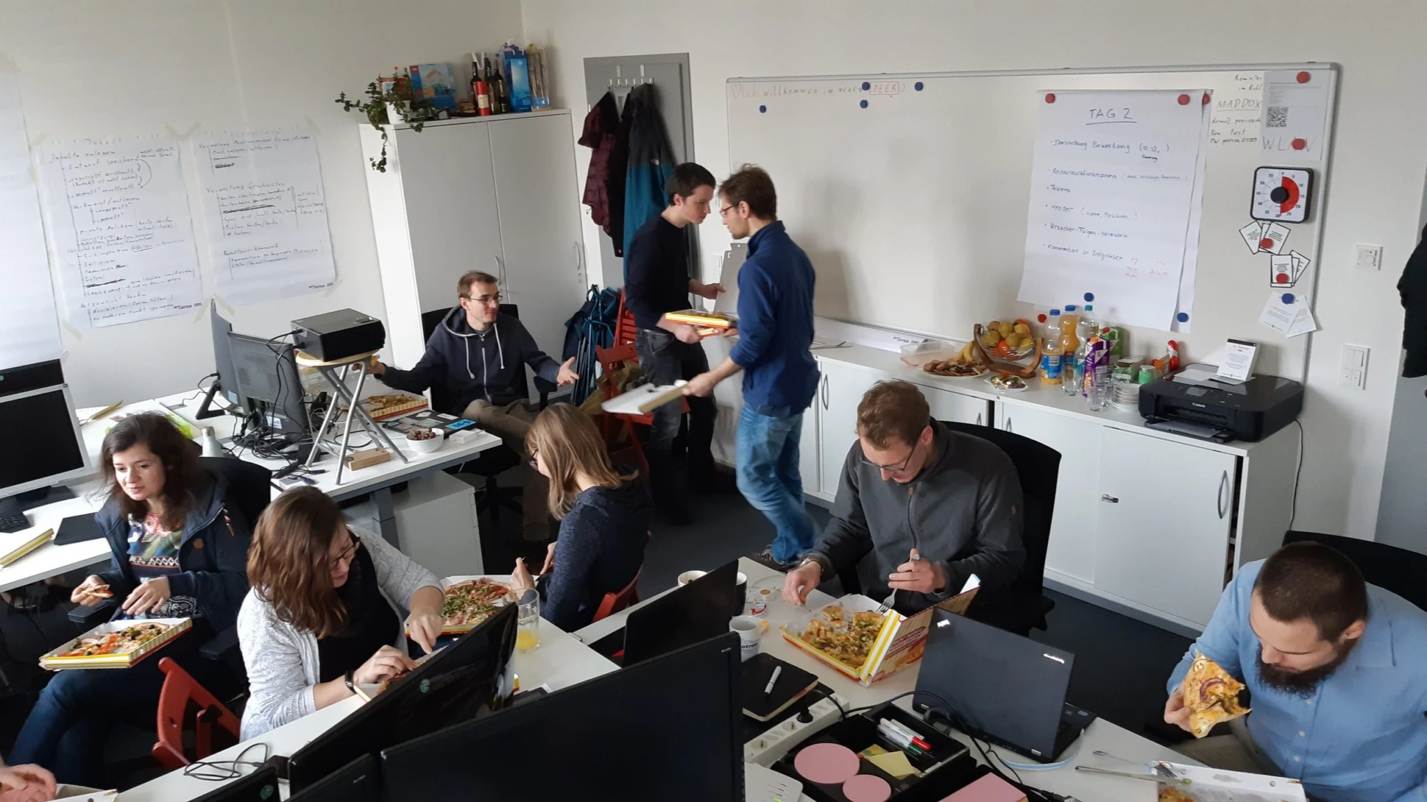 Peerox-Team isst gemeinsam Pizza im Büro während einer Coding-Camp-Pause.