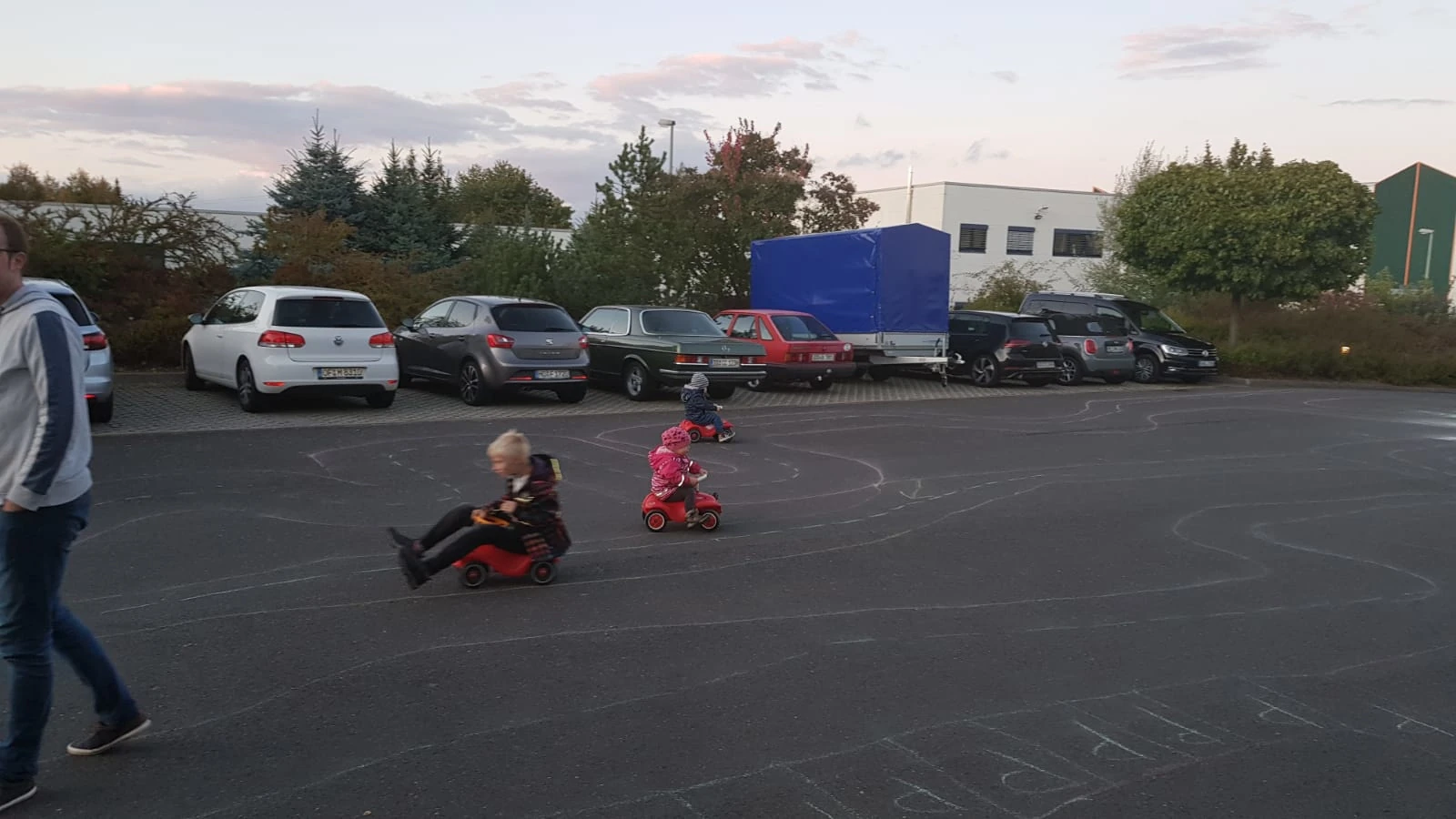 Kinder beim Sommerfest beim Fahren mit Tretfahrzeugen auf einem abgesperrten Bereich.