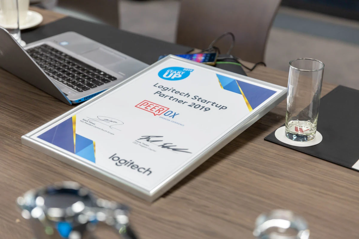 Ausgezeichnete Urkunde von Peerox beim Logitech Startup Wettbewerb 2019 auf Konferenztisch